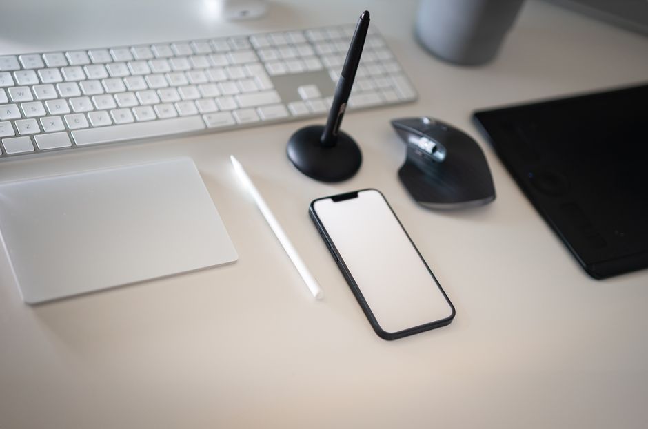 Clean and modern workspace featuring keyboard, smartphone, and wireless mouse with minimalistic design