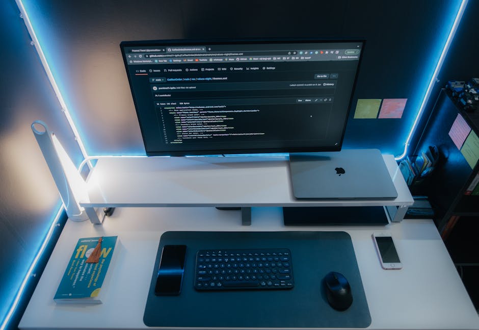 A minimalist workspace with a computer setup and neon lighting