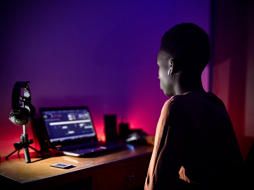 A teenager using a laptop with purple ambient lighting