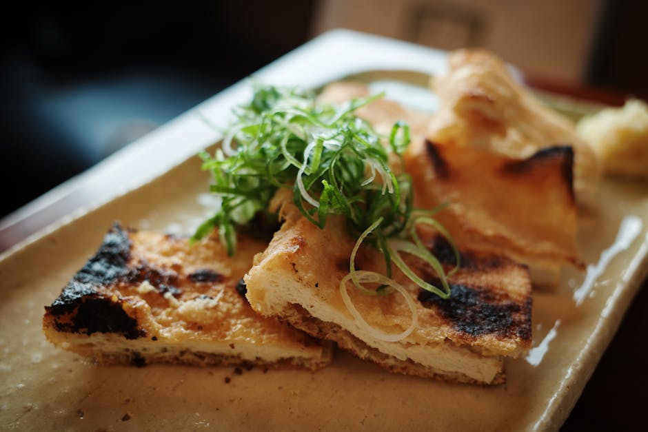Delicious grilled tofu topped with fresh scallions on a ceramic plate in a Kyoto restaurant.