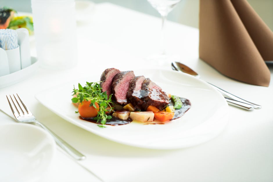 A beautifully presented beef steak with vegetables and sauce in a fine dining setting
