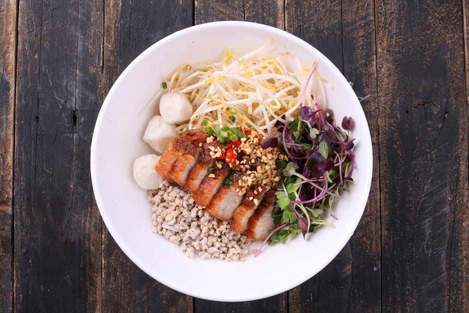 A vibrant Asian fusion dish featuring pork, veggies, and noodles in a white bowl