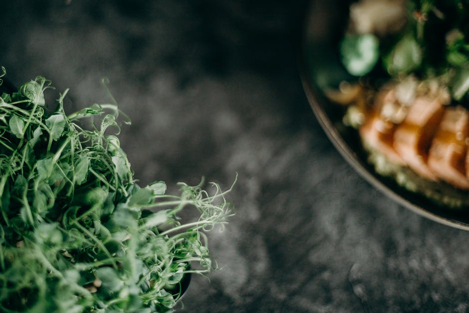 A close-up view of fresh green vegetables with a dish in the background, showcasing healthy eating.